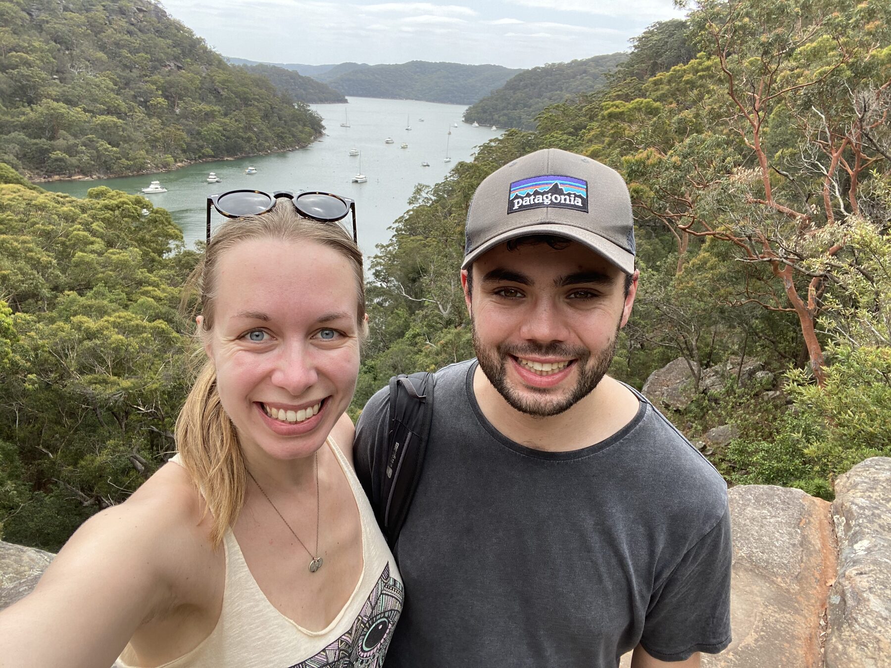 Tom and Alana smiling in front of a coastal view